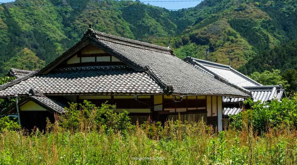 old Japanese house and roof tiles surrounded by overgrown lawn