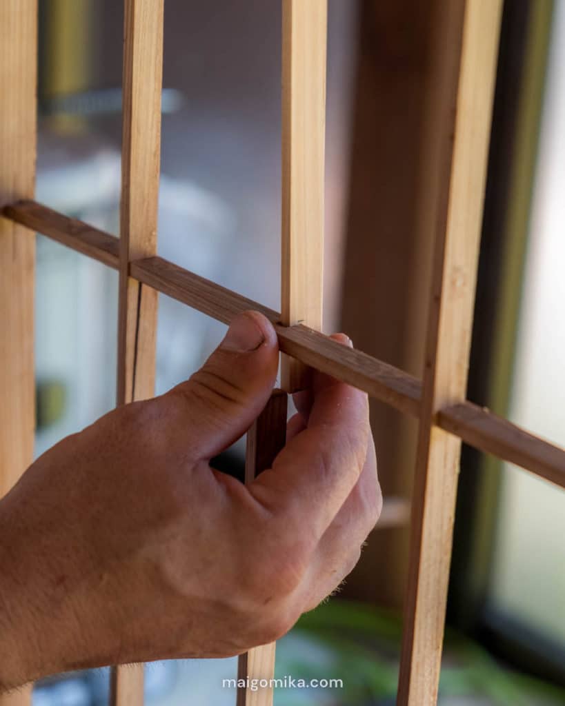 man's hands fitting fixed slate into Japanese shoji screen repair for House Renovation