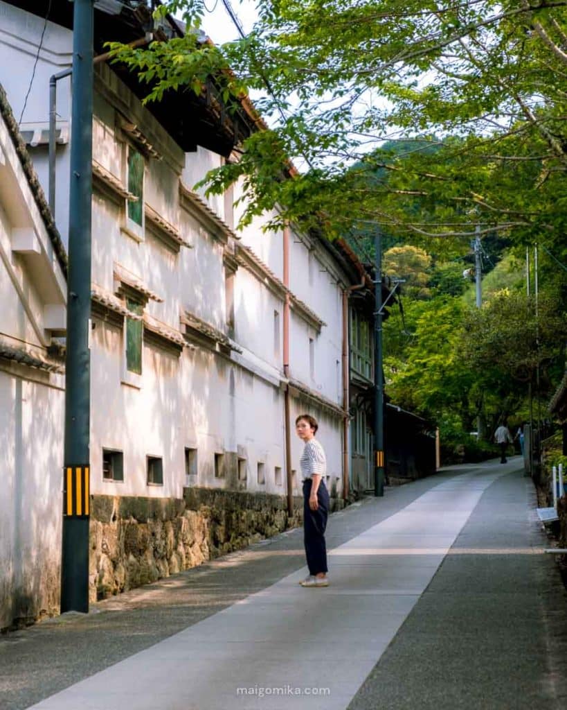 woman standing in the middle of a historic street along whtie sake breweries in Sakawa Town, Kochi Prefecture, Japan