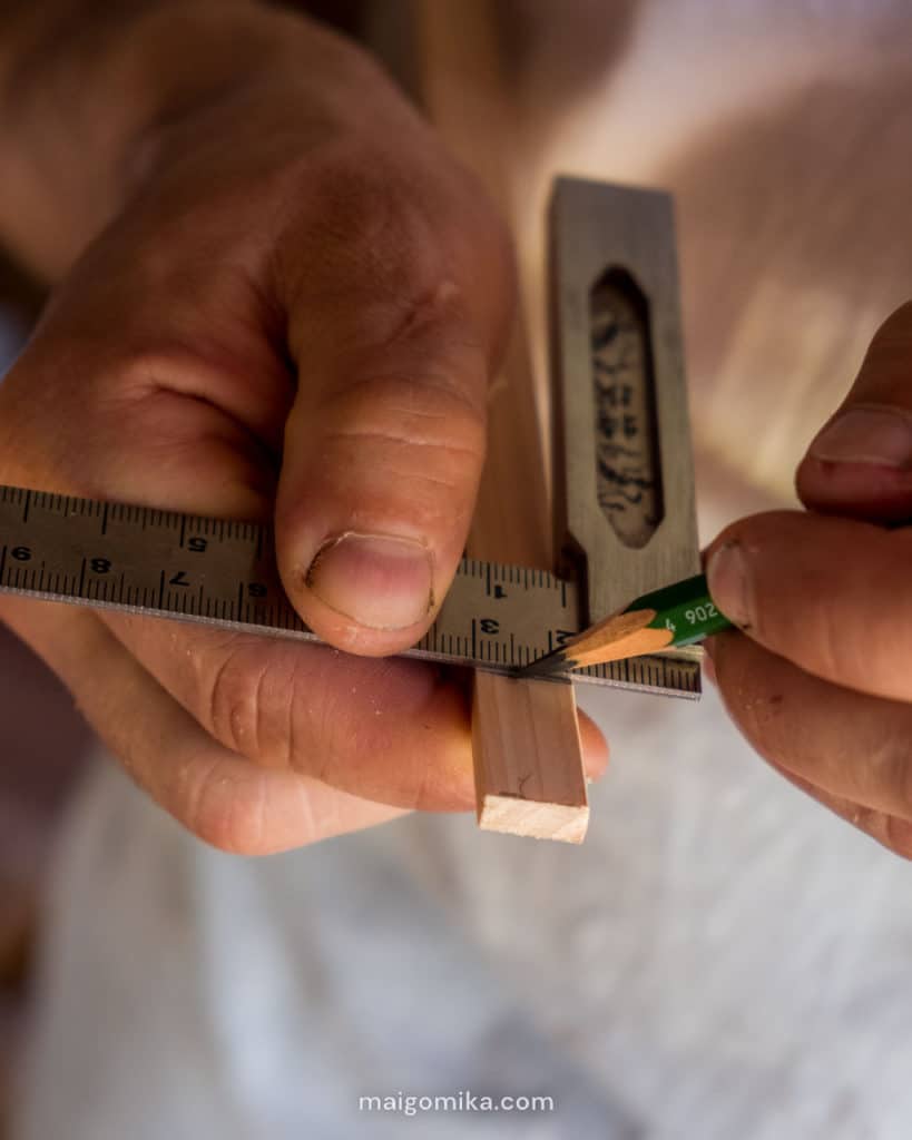 man's hands marking pencil line on wood slate for Japanese House Renovation