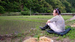girl sitting by edge of rice field on picnic blanket in japan