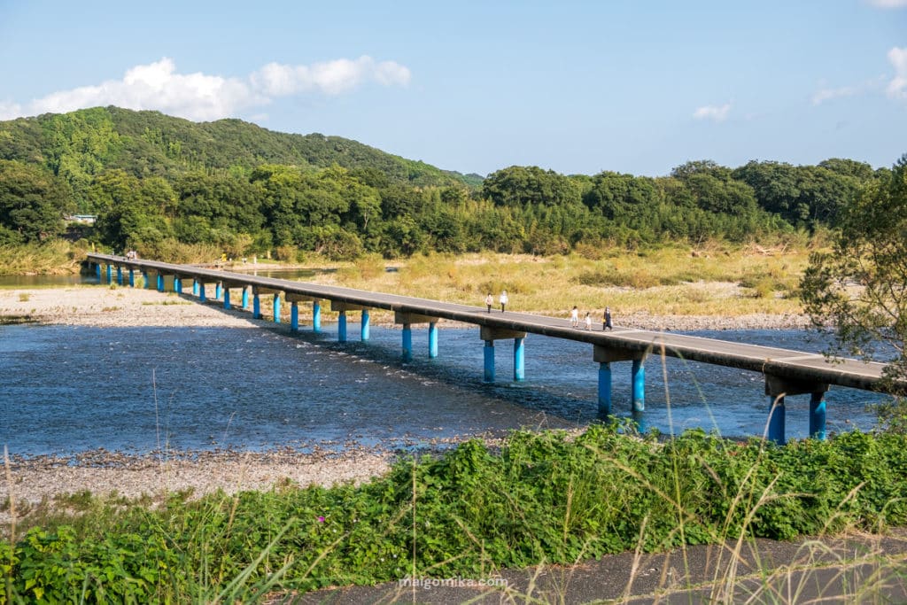 people walking on cement bridge called chinkabashi in kochi prefecture with blue water and mountain background