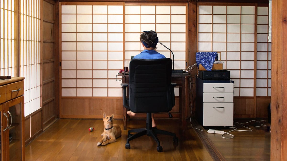 woman sitting at desk with japanese screen doors in background and small dog in corner