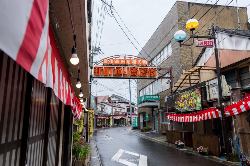 Street signage on Showa no Machi, Oita prefecture, along the old shopping street, with amber and turquoise lights in the distance.