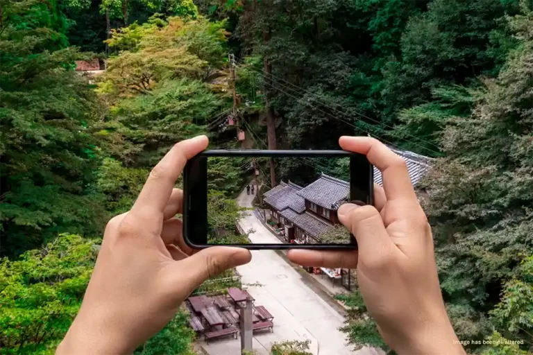 two hands holding a smart phone taking picture in the countryside of Japan
