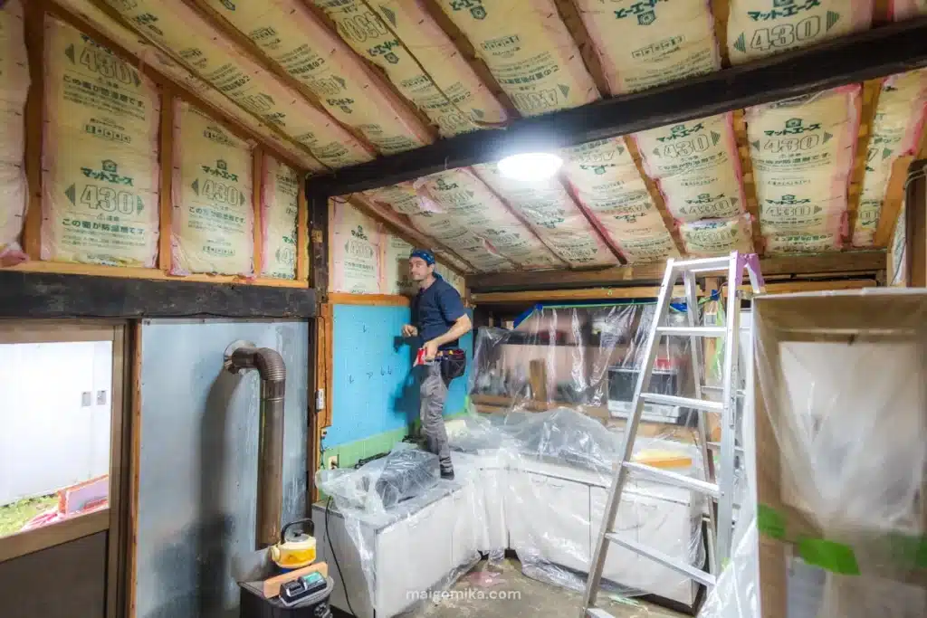 man installing insulation in a ceiling of an akiya house in Japan